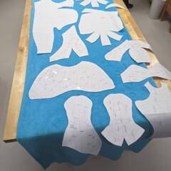 A photograph of paper patterns laid out on fabric to be cut.