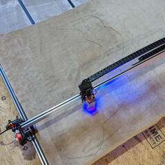 A photograph of a laser cutter cutting through tan fabric.