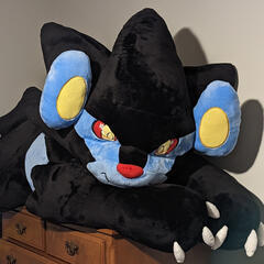 A photograph of an enormous plush lynx perched atop a bedroom dresser.