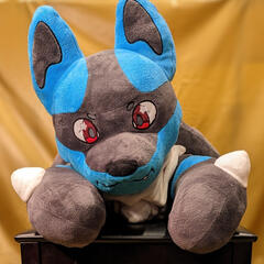 A photograph of a chunky plush jackal peering over the back of a bench.