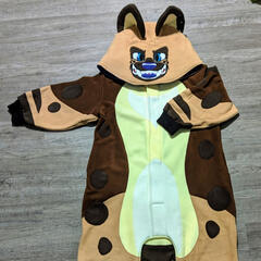 A photograph of a kigurumi styled after a brown spotted hyena with a large toothy grin.