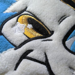 A close photograph of a machine-embroidered eye in a toony style.
