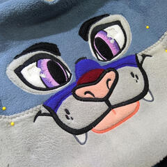 A close photograph showing the machine embroidered face of a stylized lynx.