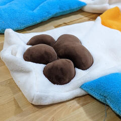 A photograph of chunky fabric pawpads on the arm of an unfinished plush.